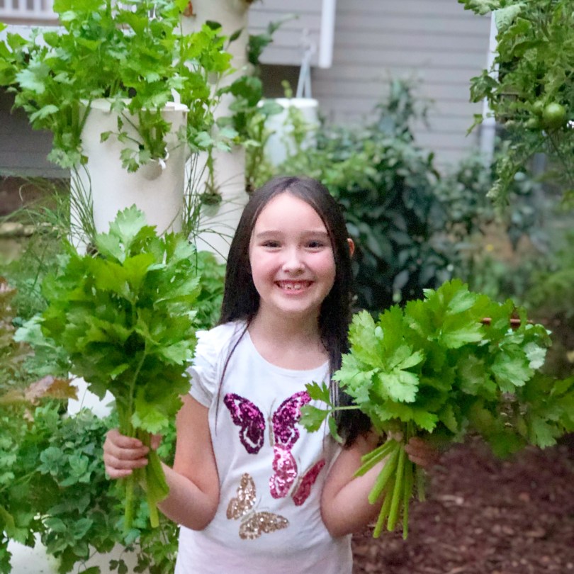Happy little girl double-fisting celery harvest